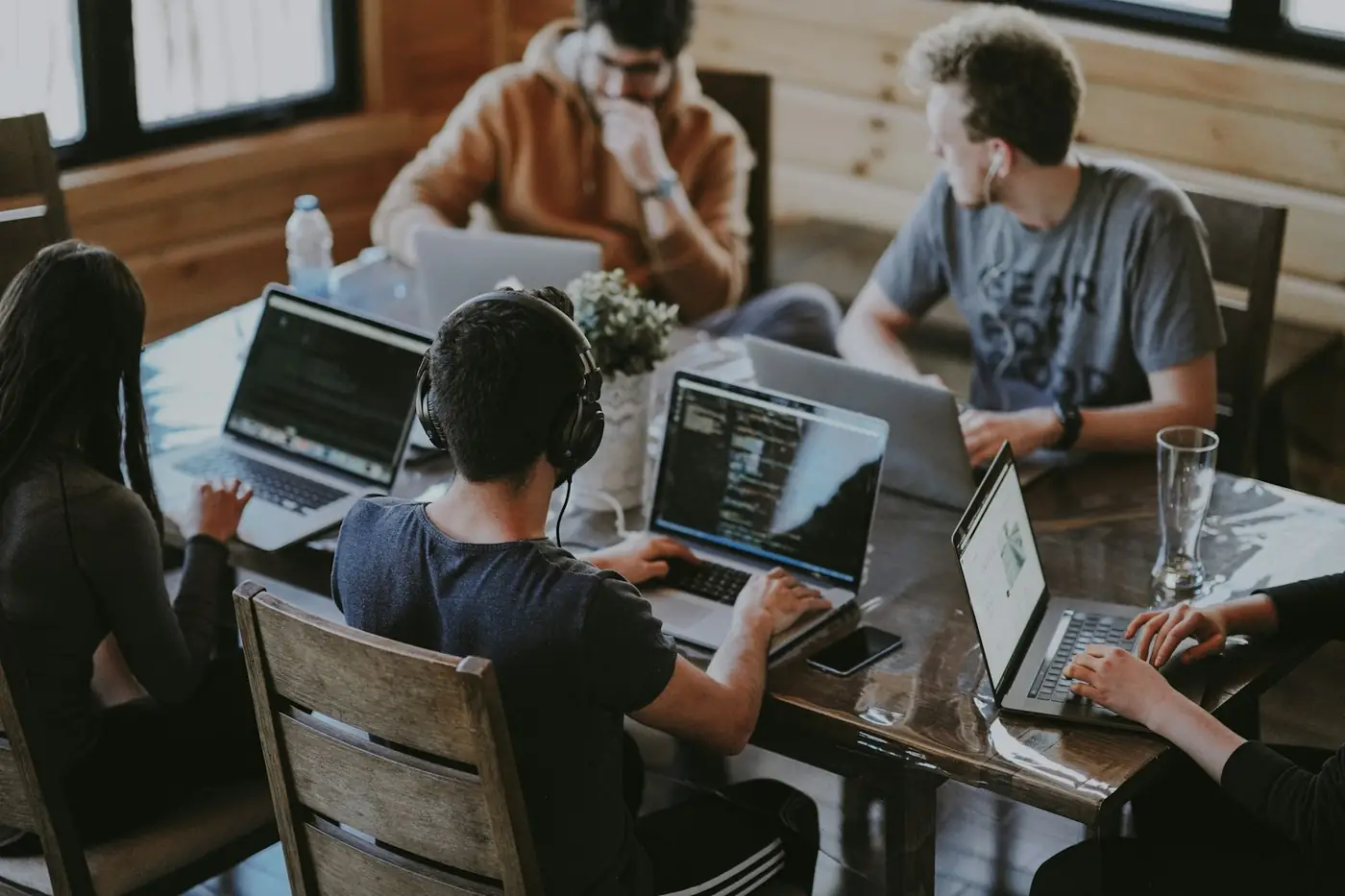 Team members working together on laptops around a wooden table
