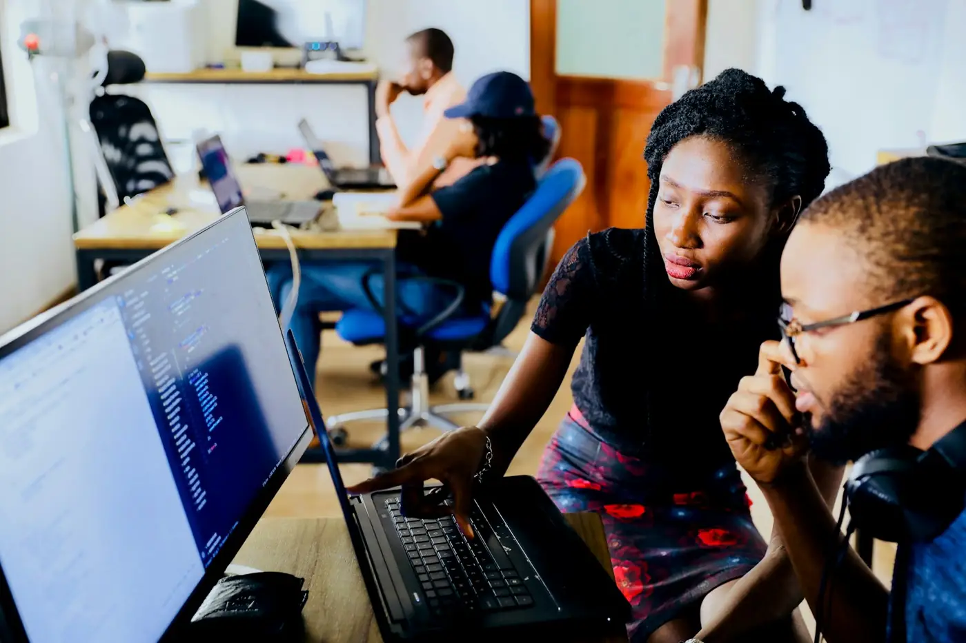 Two developers reviewing code together on a laptop screen