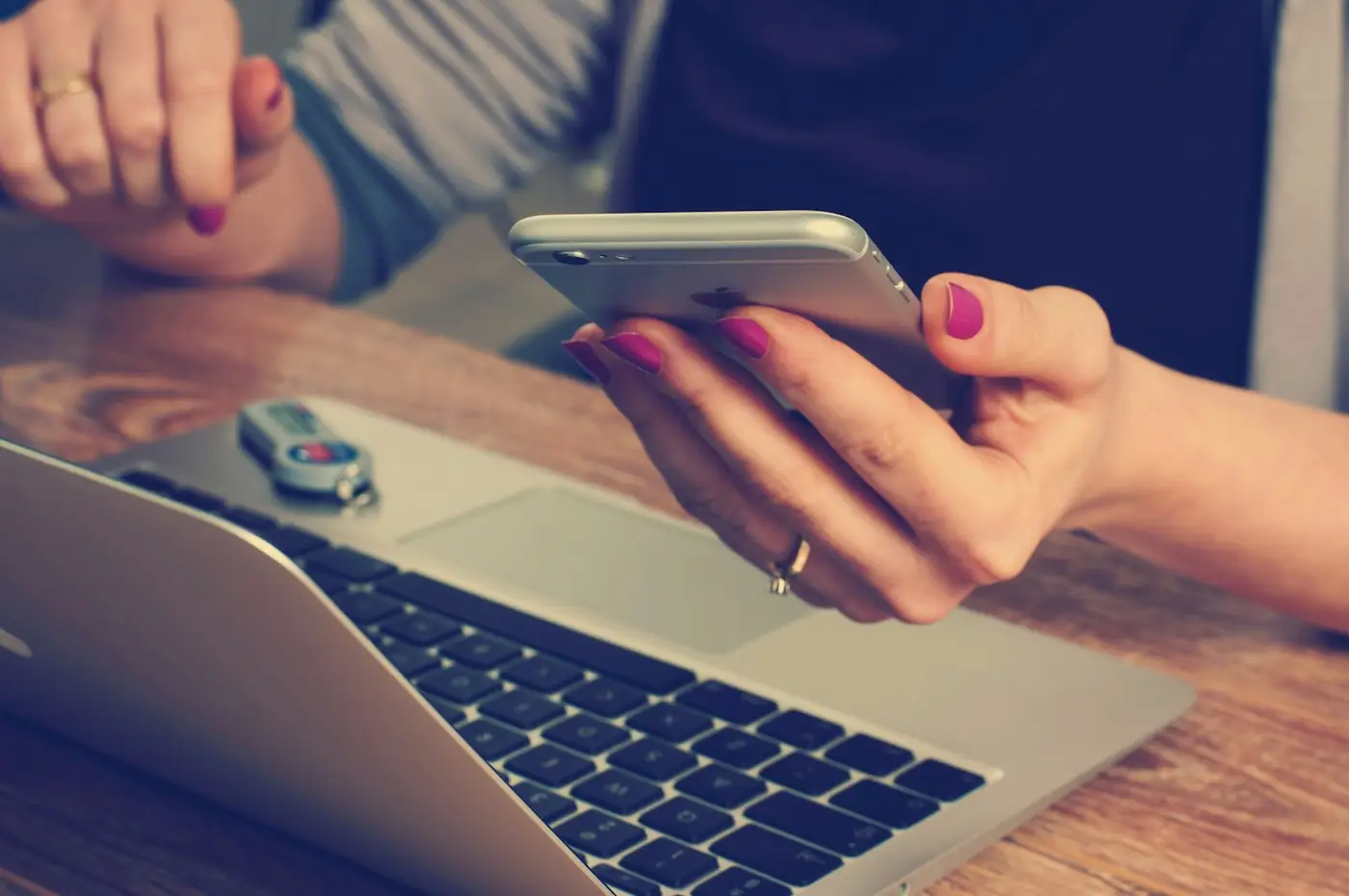 Client checking messages on a phone beside a laptop