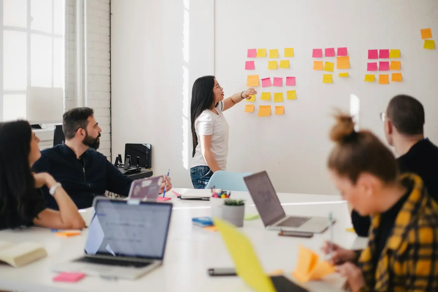 Marketing team planning a campaign around a whiteboard covered in sticky notes