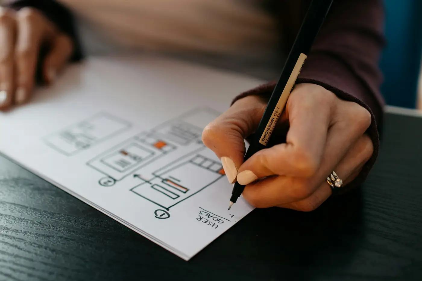 Designer sketching website wireframes by hand with a pencil